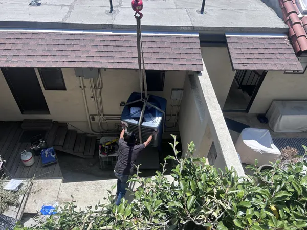 A new condenser being craned over a house